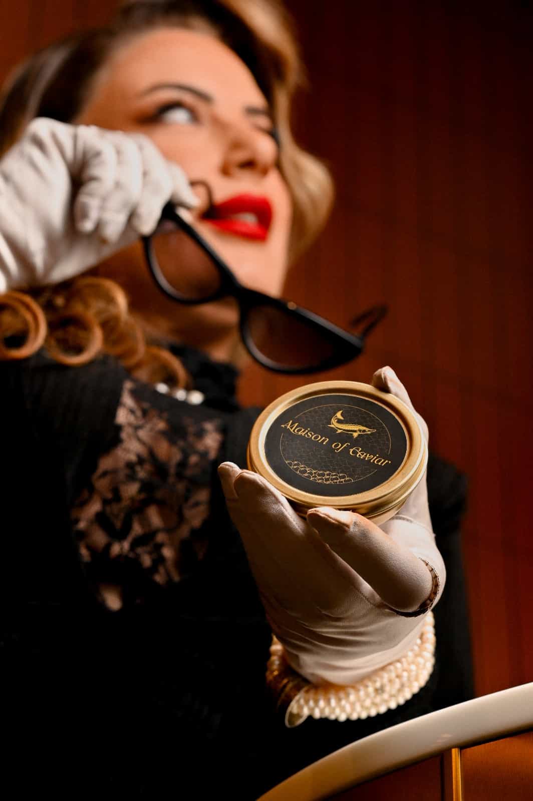 Nicole, founder of Maison of Caviar, holding a Maison of Caviar tin in white gloves